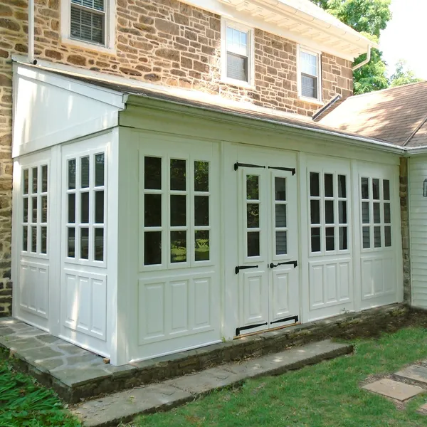 White three season porch enclosure on a stone farmhouse 